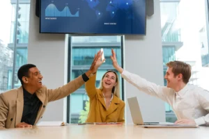 Profissionais celebrando o sucesso de um projeto após superar desafios de mudança organizacional, representando a aplicação da curva de Kübler-Ross na gestão da resistência à mudança.