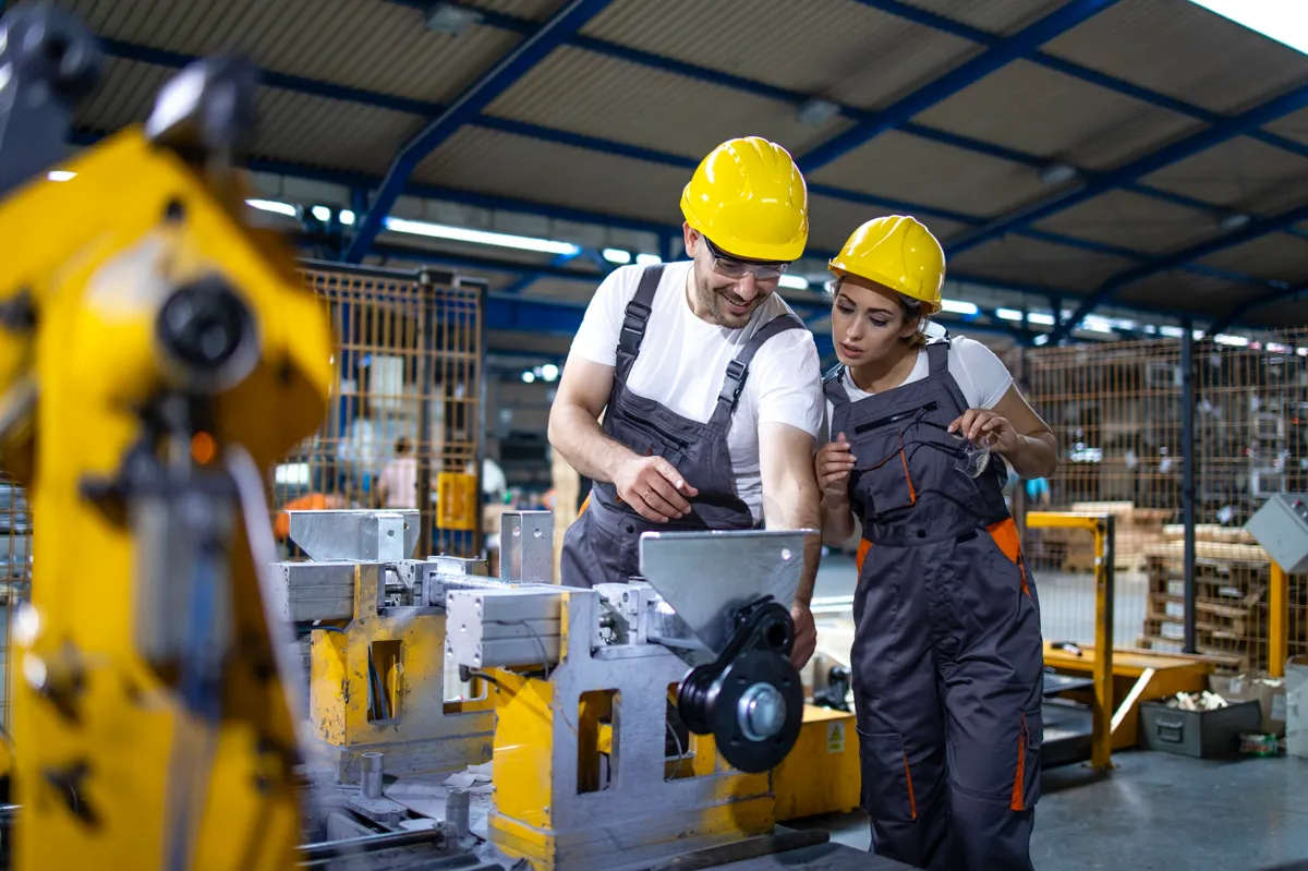Dois profissionais em ambiente industrial discutindo o planejamento para implementação do TPM.
