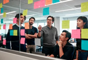 Profissionais realizando sessão de brainstorming com post-its coloridos em um ambiente corporativo moderno, representando colaboração e inovação na melhoria de processos.