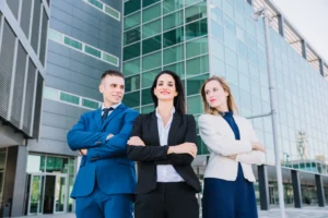 Três profissionais corporativos posicionados em frente a um edifício moderno, representando competência e certificação Green Belt em melhoria contínua.