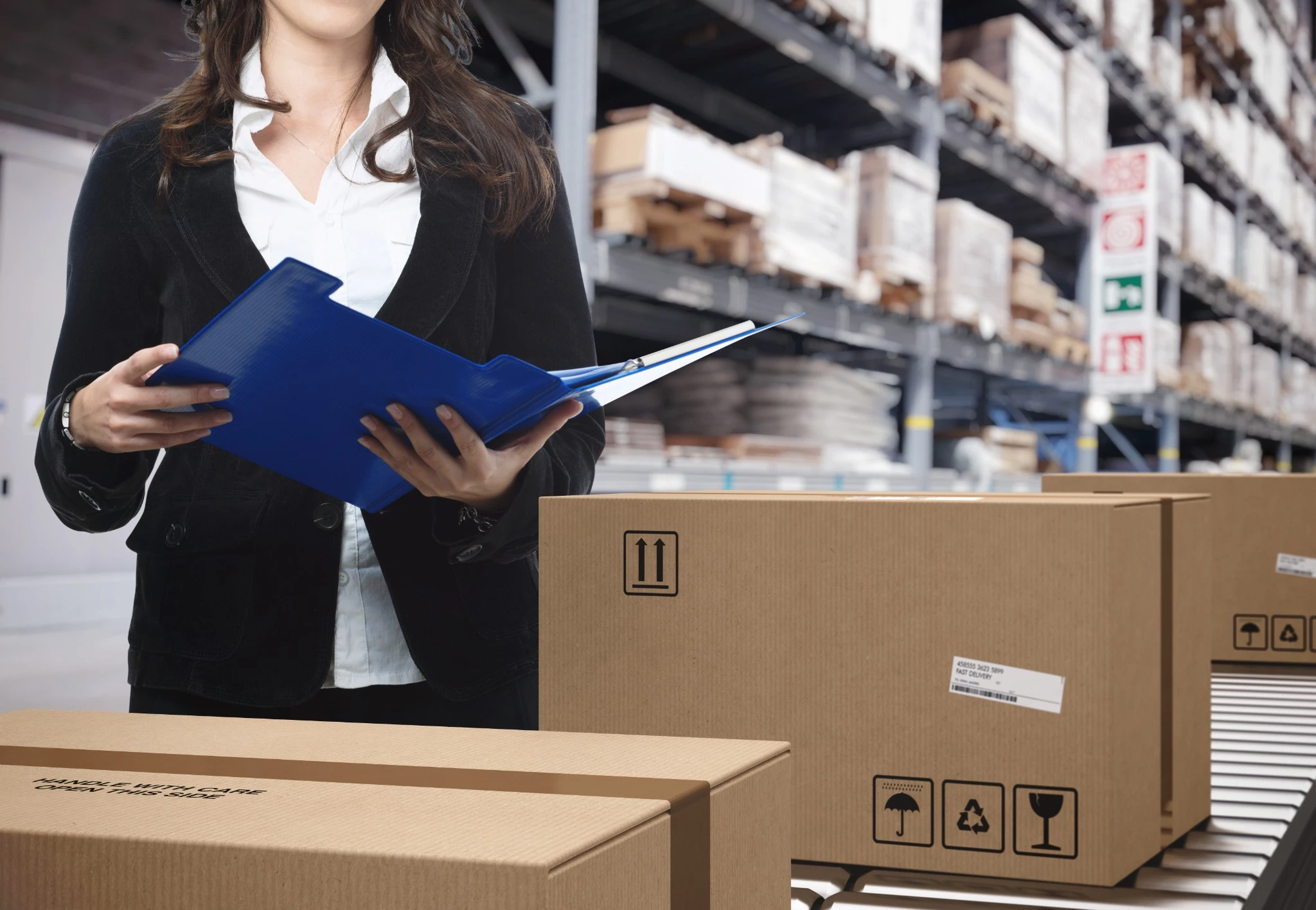 Profissional conferindo documentos no setor logístico e analisando embalagens em armazém industrial