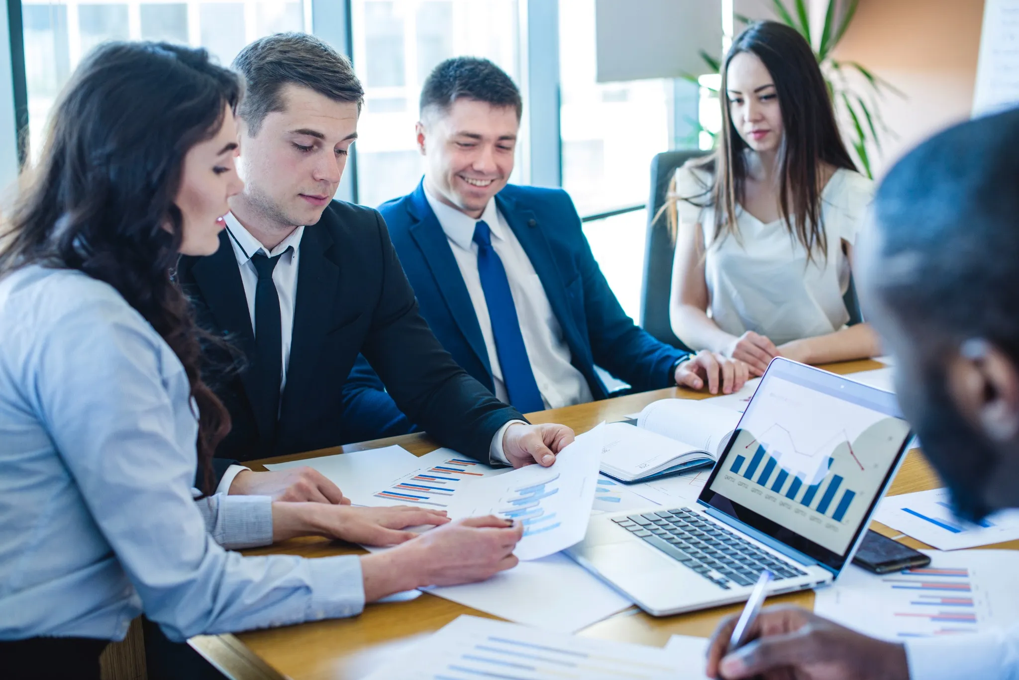 Profissionais em reunião analisando gráficos e relatórios financeiros, representando o curso Combo Administração: Gestão, Finanças e Excel.