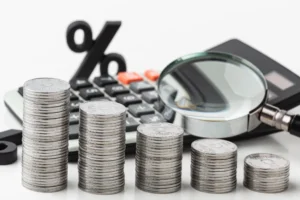 Cálculo do Custo de Produção com pilhas de moedas e calculadora representando análise financeira industrial