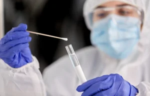 Profissional realizando coleta por swab para verificar resíduos em validação de limpeza, representando práticas de controle de contaminação em indústria farmacêutica.