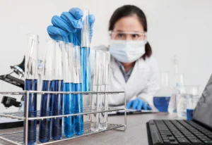 Cientista realizando análises laboratoriais com tubos de ensaio em validação de procedimentos analíticos segundo o ICH Q2(R2)