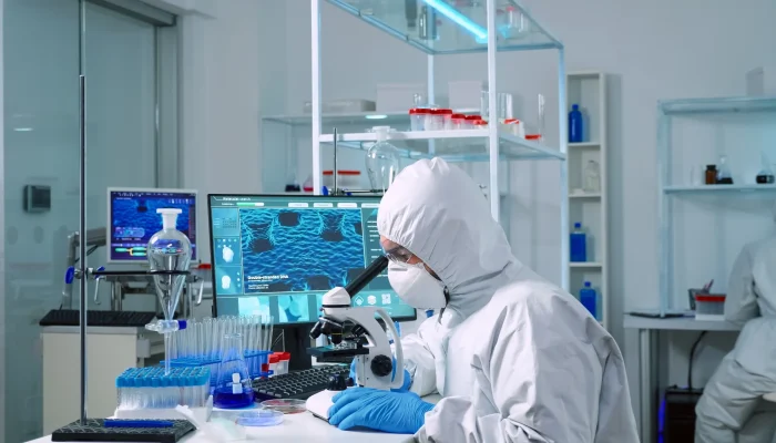 Pesquisador em laboratório analisando amostras no microscópio com tecnologia aplicada à nanotecnologia farmacêutica